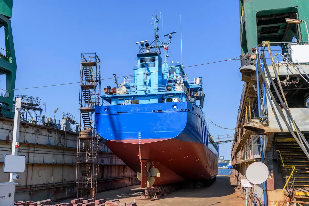 A damaged cargo ship is being repaired in the port area